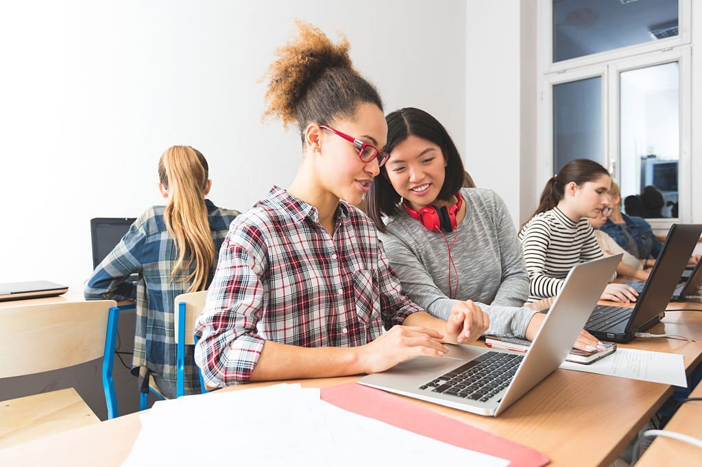 Multi ethnic female students coding on laptops in a computer lab.